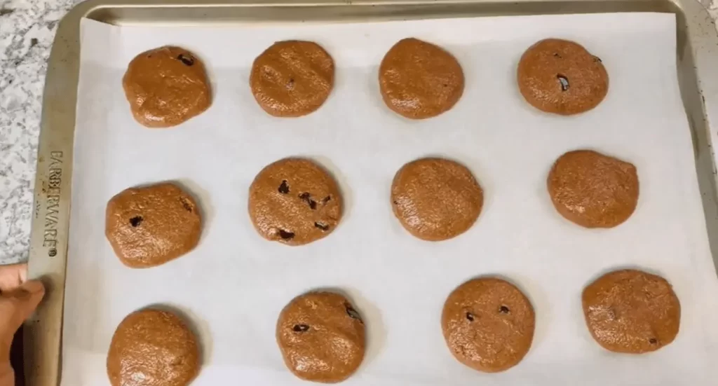 Ingredients for protein powder cookies, including protein powder, flour, and chocolate chips, laid out on a kitchen counter