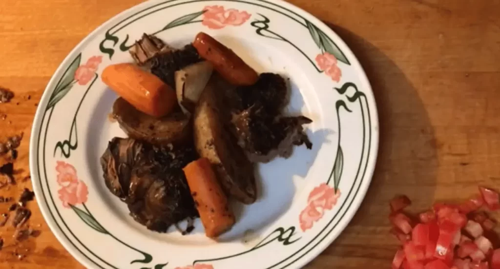 Finished beef chuck roast served with carrots, potatoes, and gravy. 