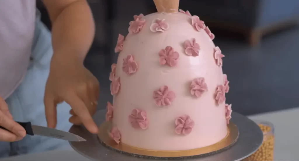 Barbie cake with a pink fondant dress and elegant decorations on a cake stand.