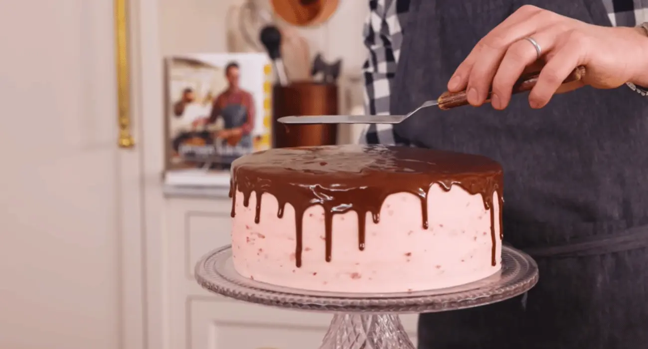 A slice of moist strawberry chocolate cake with a rich chocolate frosting and fresh strawberry garnish