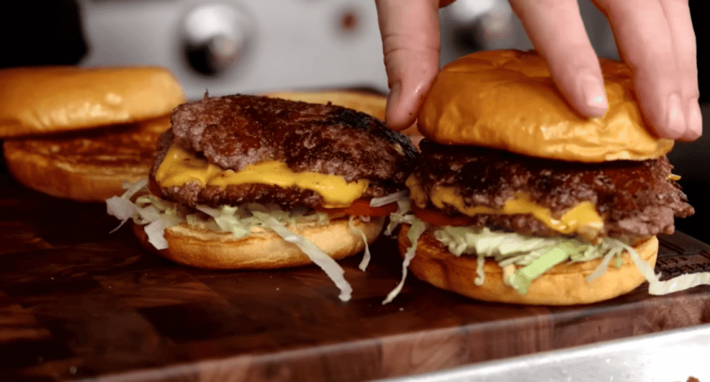 Juicy cheeseburger with a perfectly grilled beef patty, melted cheddar cheese, fresh lettuce, tomato, and pickles, all nestled in a toasted bun.