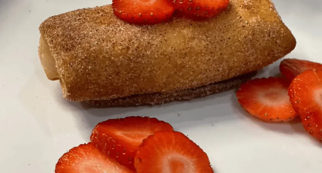 Strawberry Cheesecake Chimichangas dusted with powdered sugar and garnished with fresh strawberries.