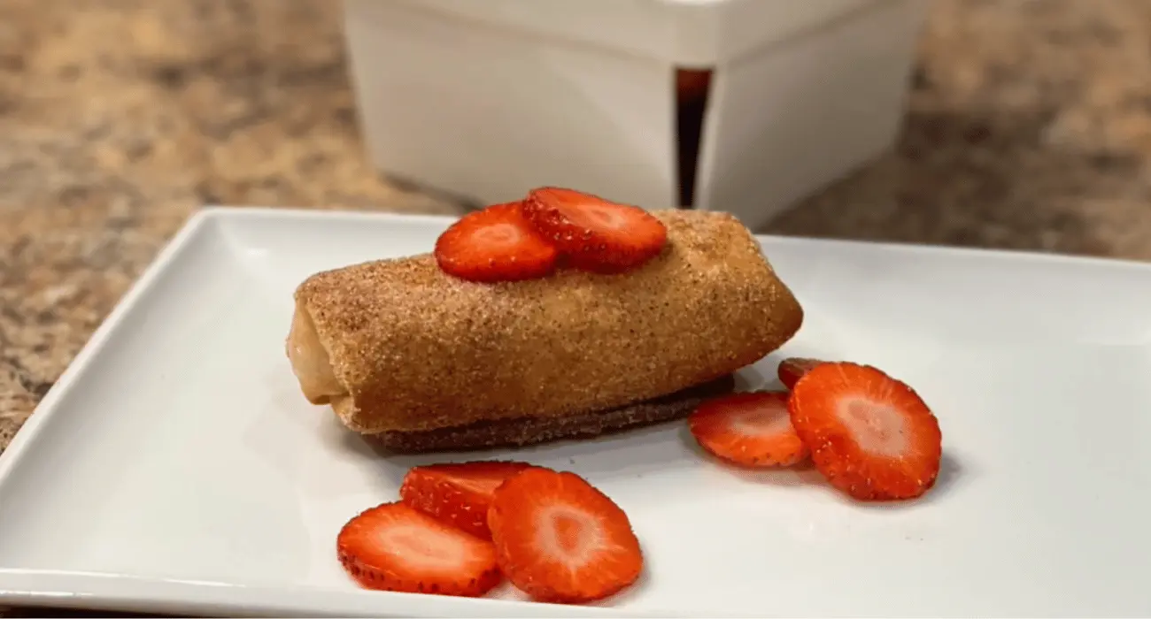 Strawberry Cheesecake Chimichangas dusted with powdered sugar and garnished with fresh strawberries.